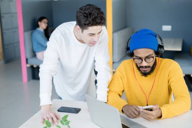 Modern ofiste çalışırken Gadget uygulamasını kullanarak ve tartışarak ciddi düşünceli adamlar