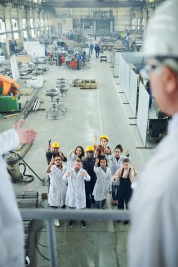 Grev sırasında protesto eden çok ırklı işçi grubuna yüksek açı görünümü balkonda duran iki fabrika yöneticisine bakarak, kopya alanı