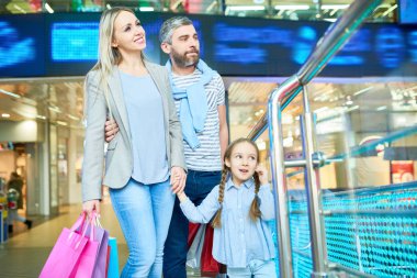 Alışveriş merkezinde küçük kız alışveriş ile modern ailenin portresi, çanta tutan gülümseyen kadın odaklanmak