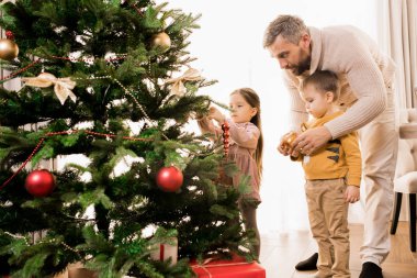 İki sevimli çocuk ile Noel ağacı dekorasyon mutlu baba sıcak tonlu portre, kopya alanı