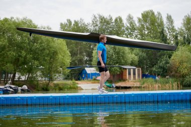 Genç kanocu onun kayık ve kürek ile iskele boyunca yürüyüş