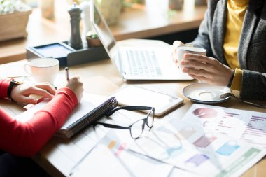 Kafede iş analitiği ile çalışırken, pazarlama kağıtlarıyla dolu masada oturup projeyi tartışan tanınmayan iş kadınlarının yakın çekim