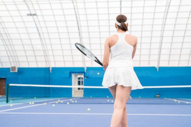 Kapalı mahkeme, kopya alanı eğitim sırasında raket tutan kadın tenis oyuncusu arka görünüm portre