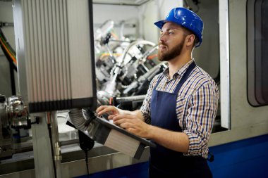 Kontrol paneli ne butona basarak sabit hat takan makine operatörünün yan görünüm portresi, kopyalama alanı
