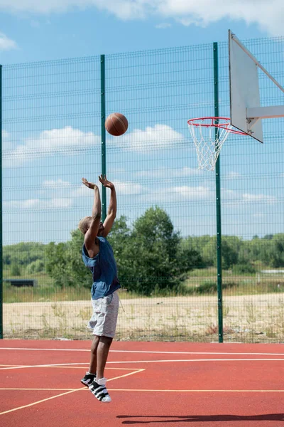 stock image Side view action shot of African man jumping in basketball court scoring points, copy space