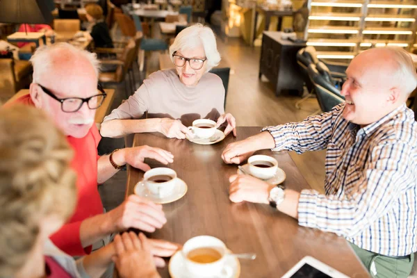 カジュアルな服装で幸せな先輩のグループがカフェに集まり 最後のニュースを話し合い お茶を飲む — ストック写真