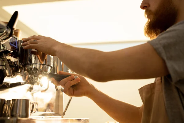严重忙碌的胡须咖啡师在围裙的特写 在咖啡馆冲煮咖啡时 将Portafilter连接到浓缩咖啡机 — 图库照片