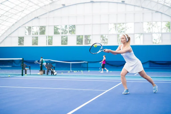 女性テニス選手のフルレングスアクション屋内コートでのトレーニング中にジャンプでラケットを振る コピースペース — ストック写真