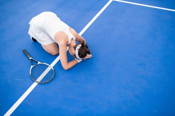 テニスコートで床に座っている疲弊した若い女性の高アングルポートレート息をのむ コピースペース — ストック写真