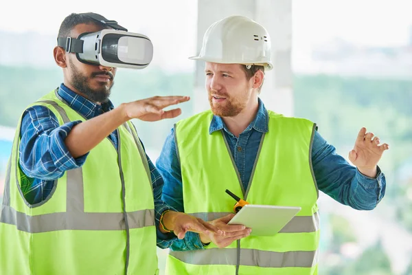 Görselleştirme oluşturmak için Vr simülatörü kullanırken sakallı gesturing ile konsantre yakışıklı karışık yarış mühendisi, meslektaşı ona proje açıklayan