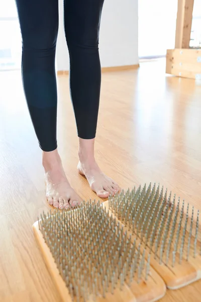 Close-up of unrecognizable woman in leggings preparing for standing on nails, she practicing yoga alone