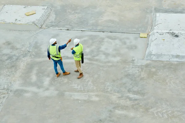 建設現場と計画プロジェクトのコンクリートの床に立っている2人の労働者の上見の肖像画 コピースペースの背景 — ストック写真