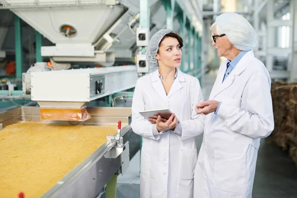 两名女工在食品厂进行生产质量检查的肖像 她们站在传送带上 使用数字平板电脑 复制空间 — 图库照片