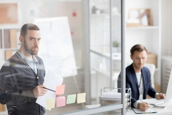 Portrait Thoughtful Bearded Man Planning Work Sticking Notes Glass Wall — Stock Photo, Image