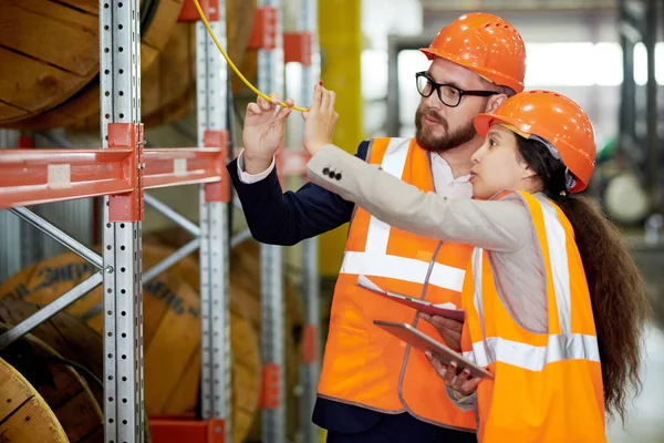 Portrait of two modern factor workers wearing hardhats doing inventory in production warehouse, copy space