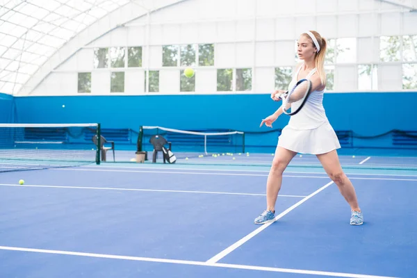 室内コートでの訓練中にラケットをかざすブロンド女子テニス選手の全長ポートレート コピースペース — ストック写真