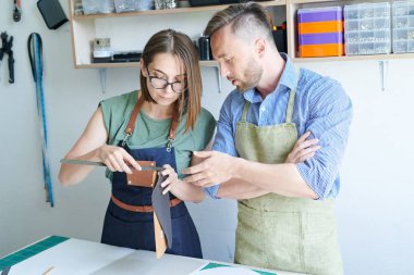 Atölyede deriden ürün yapan önlüklerde duran iki iş arkadaşı