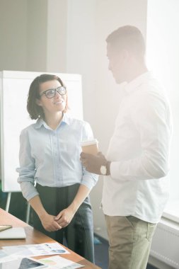 Pozitif kendinden emin çok ırklı pazarlama uzmanları masada duran ve modern ofiste kahve içerken yeni ürün satışlarını tartışıyor