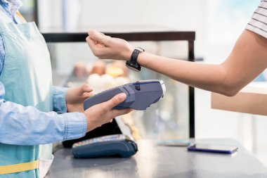 Mağaza veya kafede siparişi için Nfc üzerinden akıllı saat ile ödeme yapan tanınmayan kadının yan görünümü orta bölümü