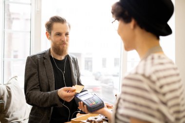 Memnun sakallı yakışıklı Cafe fatura için ödeme yaparken garson için kredi kartı veren kulaklık içerik