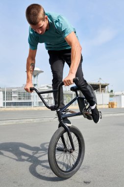 Genç adamın tam uzunlukta portre aşırı spor parkında ön tekerleğe atlama BMX stunts yapıyor