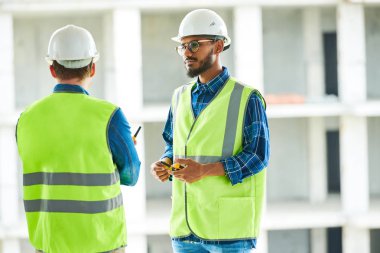Onlar apartman blok sitede ayakta iken gözlük ve hardhat özenle meslektaşları dinlerken ciddi kendinden emin orta doğu işçi