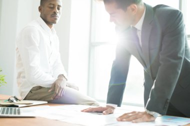 Resmi giyimde, evrakları birlikte görüntülemeye ve ofisteki toplantıda verileri tartışmaya odaklanan pensive konsantre iş arkadaşları