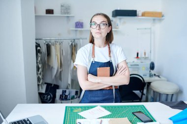 Atölyesinde kollarını çapraz bir önlük te ve genç kumaşçı portresi