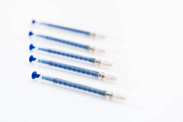 Closeup of five disposable insulin syringes in row isolated on white background, medicine and treatment concept