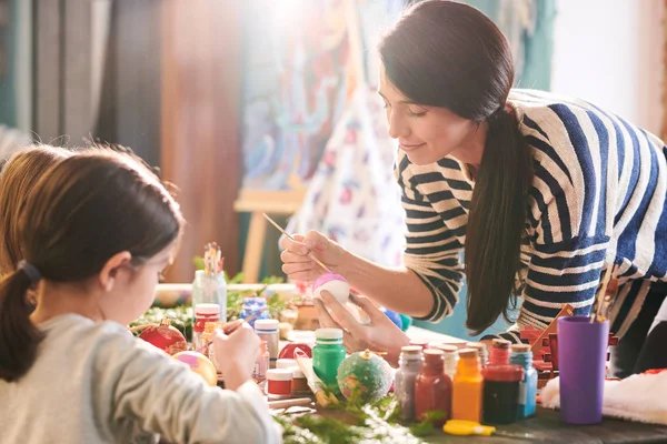 日光に照らされたアートスタジオで2人の小さな女の子と手作りのクリスマスの飾りを作る笑顔の若い女性の肖像画 — ストック写真