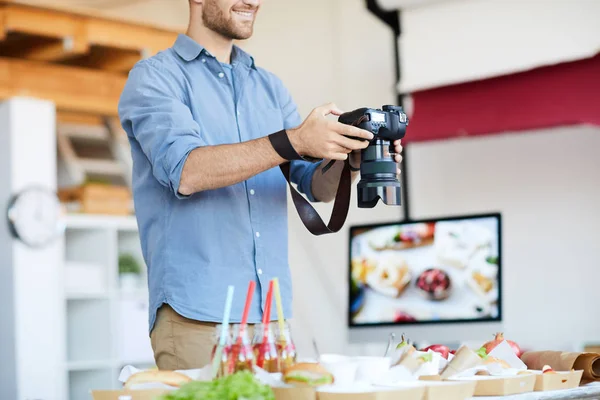 Mid-section portrait of young photographer taking photos of food while working in studio, copy space