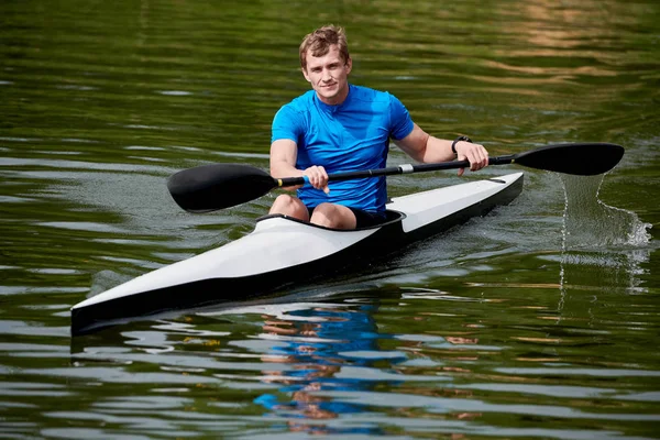 Young athlete floating on kayak on the river alone