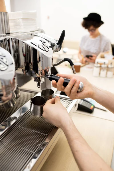 使用咖啡机制作浓缩咖啡的不可识别咖啡师的特写镜头 人用门廊过滤器连接 并拿着金属壶喝咖啡 — 图库照片