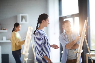 Genç emin öğretmen öğrencilerinden biri ona kroki işaret veya şövale üzerinde boyama yaparken tavsiyede