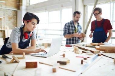 Kalem masanın üzerine yaslanmış ve çevrimiçi Montaj Çizimi görüntülerken dizüstü bilgisayarda internet kullanımı kulak ile çekici genç bayan joiner konsantre