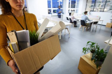 Malzeme dolu karton kutu taşıyan ve görevden sonra ofis bırakarak kazak ciddi üzgün kadın