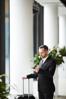 Zarif iş seyahatleri ile mesajlaşma ya da salonda uçağı için beklerken smartphone içinde kaydırma bavul