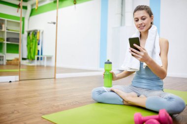 Çalışma dan sonra akıllı telefon kullanan ve gülümseyen güzel genç kadının tam uzunlukta portre, kopya alanı