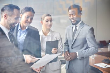Formalgiyimli kültürlerarası delegeler grubu, kağıdı okurken ve ana noktaları tartışırken bakıyor