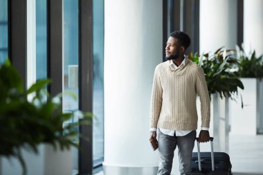 Kalkış Havaalanı lounge bırakmak rahat Afro-Amerikan olan genç adam bavul gidiyor