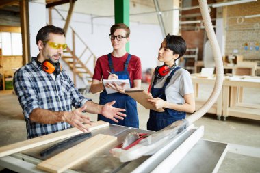 Daire testere tablo, o ile stajyer atölyesinde çalışan işaret ederken el eller ciddi emin usta marangoz güvenlik gözlüğü