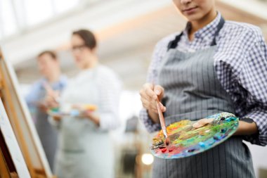 Sanat stüdyosunda şövale üzerinde resim boyama yaparken tanınmaz kadın sanatçı palet karıştırma yağ renkleri tutan orta bölüm portre, kopya alanı