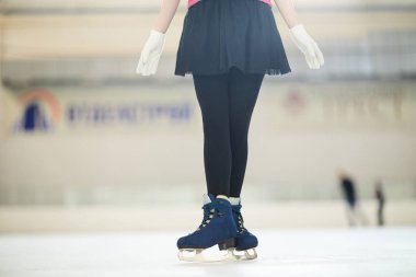 Şirin kıyafetle buz pateni pistinde duran tanınmayan artistik patinajcının düşük bölümportresi, kopya alanı