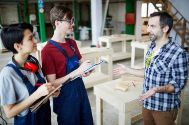 Modern atölye ayakta ve notlar genç öğrencilerle birlikte bilgi paylaşımı sırasında eller eller sakallı emin yakışıklı marangoz içerik