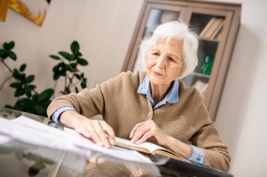 Evde masada oturan para ve mali sayma çatık yaşlı kadın portresi