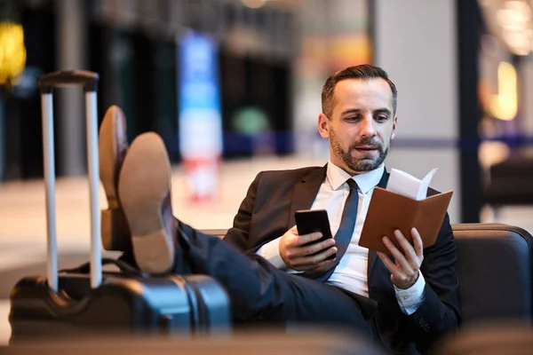 Contemporary mobile business agent looking for client number in notebook while going to make call