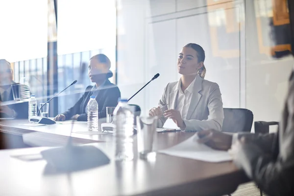 年轻优雅的女商人坐在桌旁开会 为外国同事做报告 — 图库照片