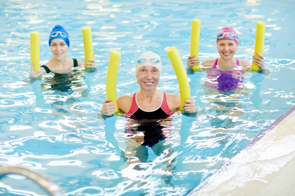 Grupa Aktywnych Seniorów Ćwiczących Basenie Trzymając Kluski Basenu Uśmiechając Się — Zdjęcie stockowe