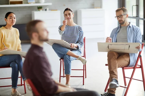 Groep Studenten Met Platen Potloden Zitten Voor Hun Groupmate Terwijl — Stockfoto