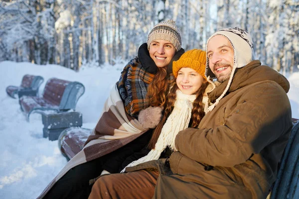 幸福家庭的肖像坐在美丽的冬季森林的长椅上 一起摆姿势 看着远方 复制空间 — 图库照片